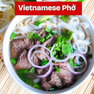 a steaming bowl of Vietnamese beef pho with clear broth tender brisket rice noodles fresh herbs and basil