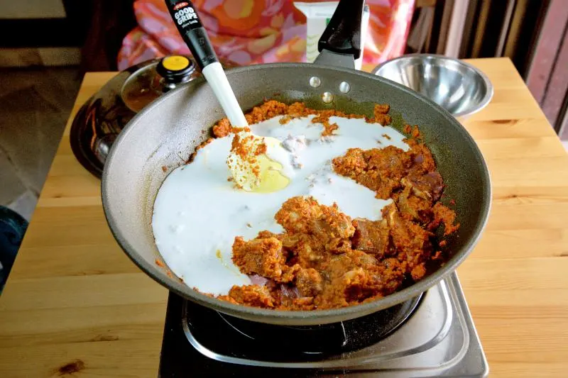  Add the coconut cream and some water to the curry paste in the wok. 