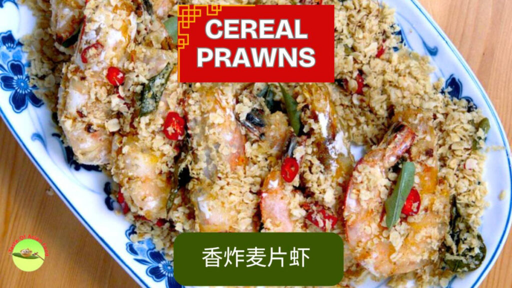 A vibrant plate of Malaysian cereal prawns, crispy and golden, garnished with fresh curry leaves and ready to serve.