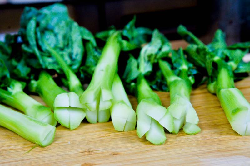 Blanched Chinese broccoli (Gai Lan) with vibrant green stalks and leaves, drained and ready for stir-frying.
